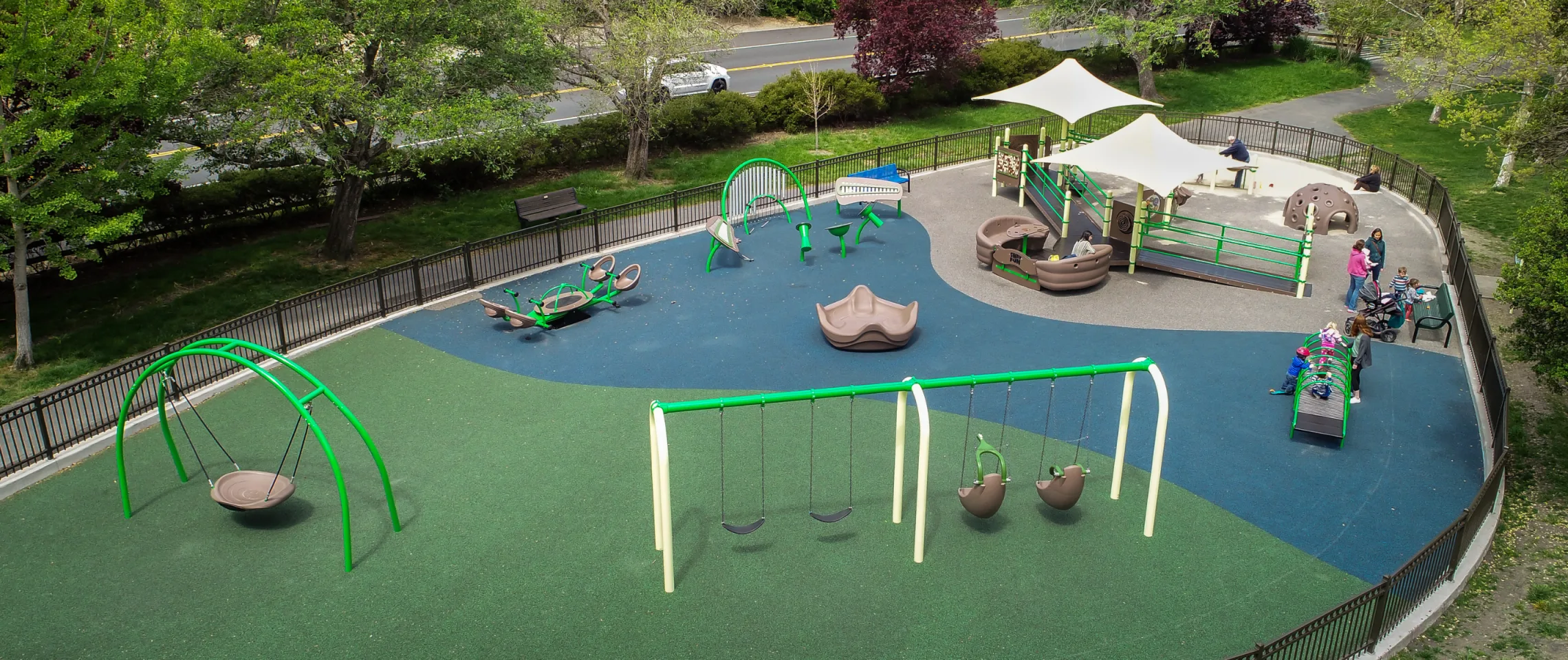 Wide view of the Lamorinda All Access Playground showing most play areas exposed to direct sun